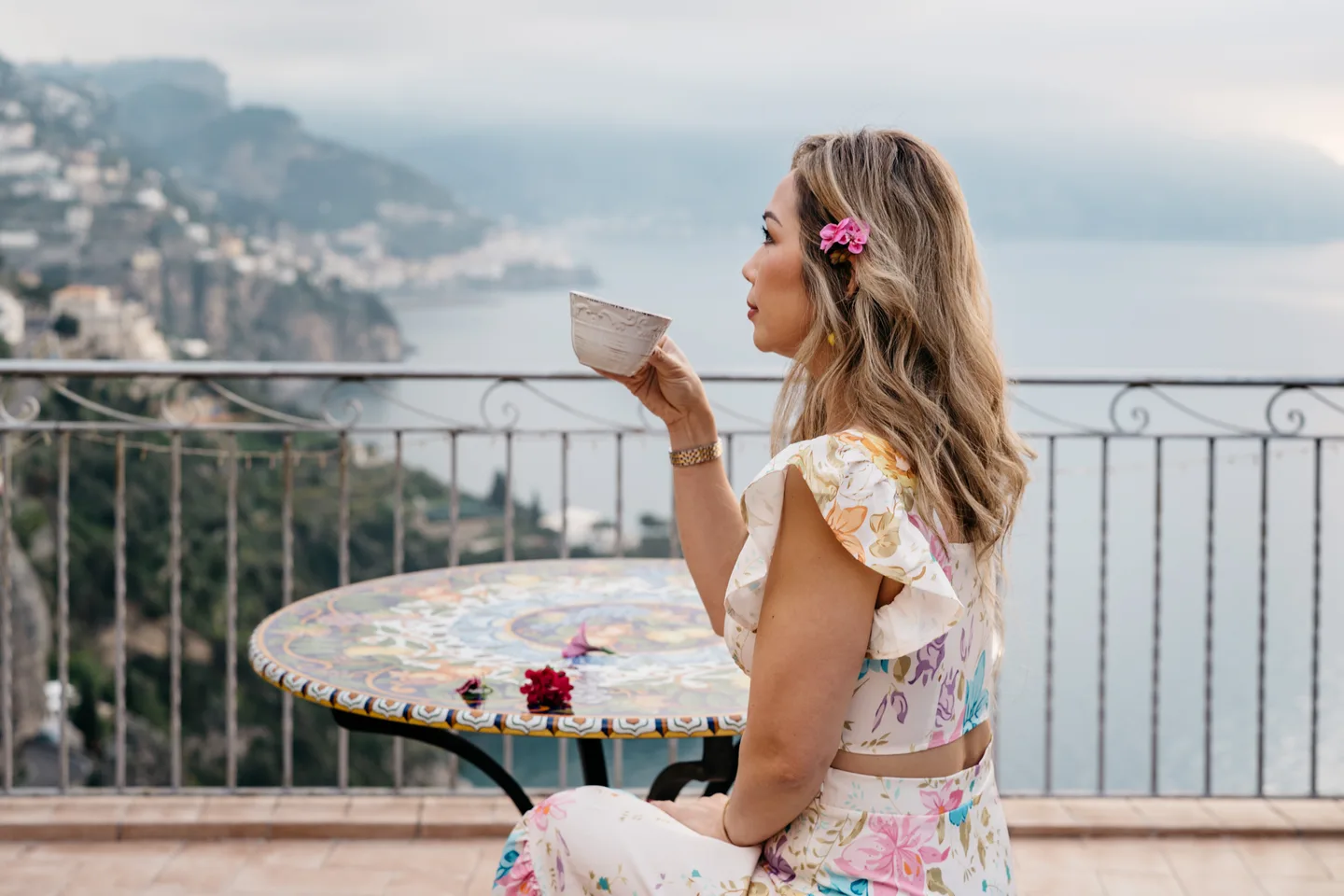 Anh holding a coffee cup above the coastal view