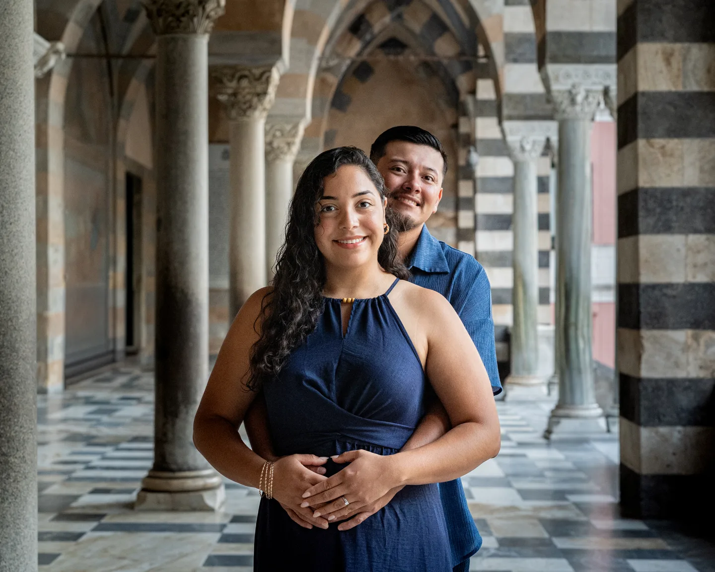 Esmeralda smiling as her companion embraces her in the cathedral portico