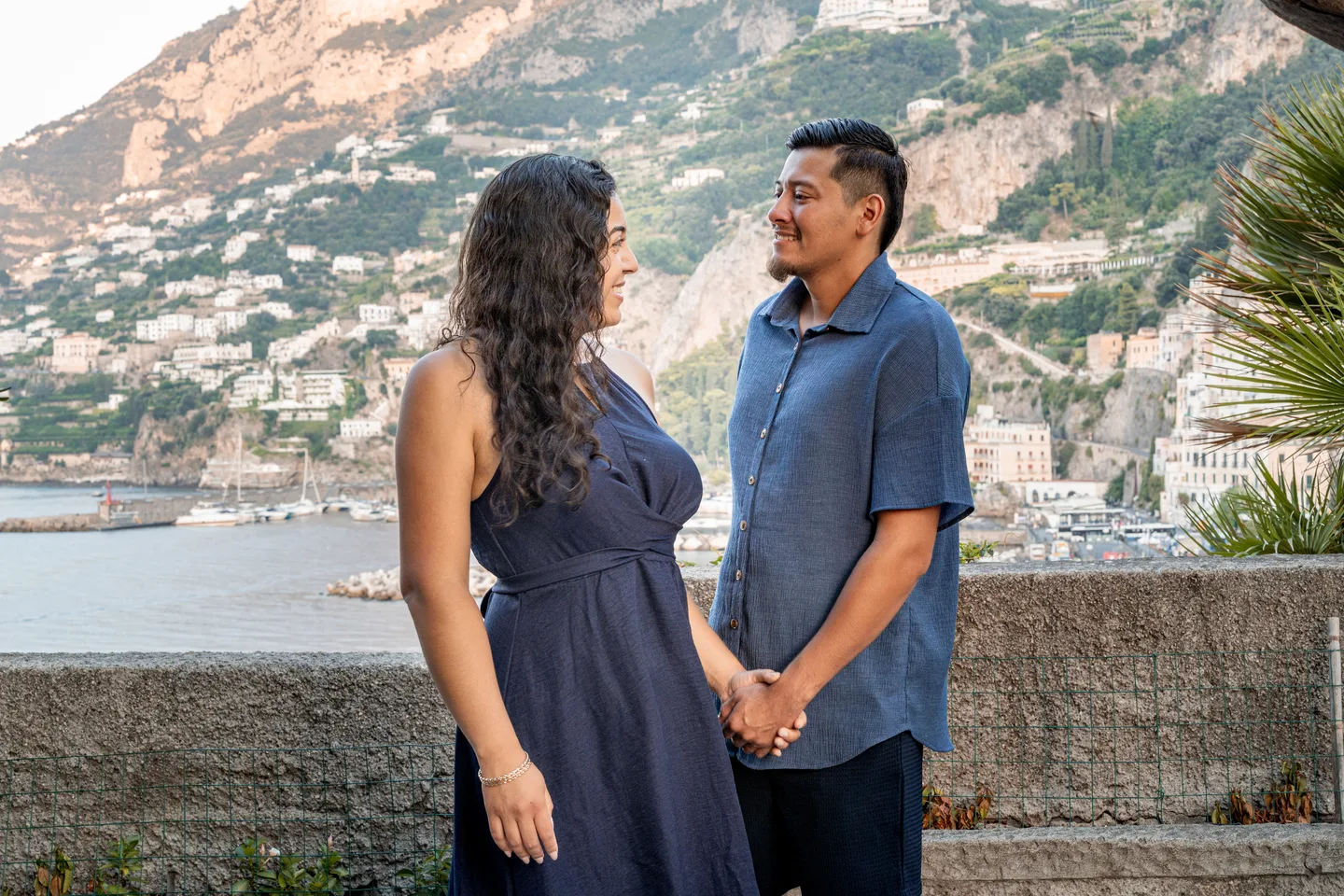 The couple holding hands and looking at one another beside the sea