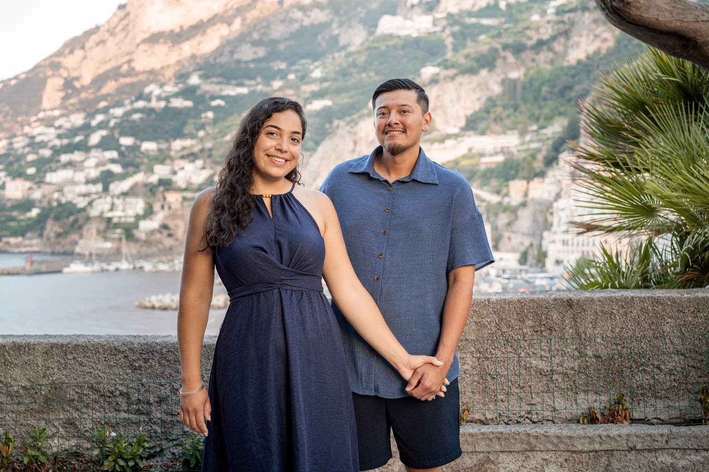 The couple side by side against the coastal hillside