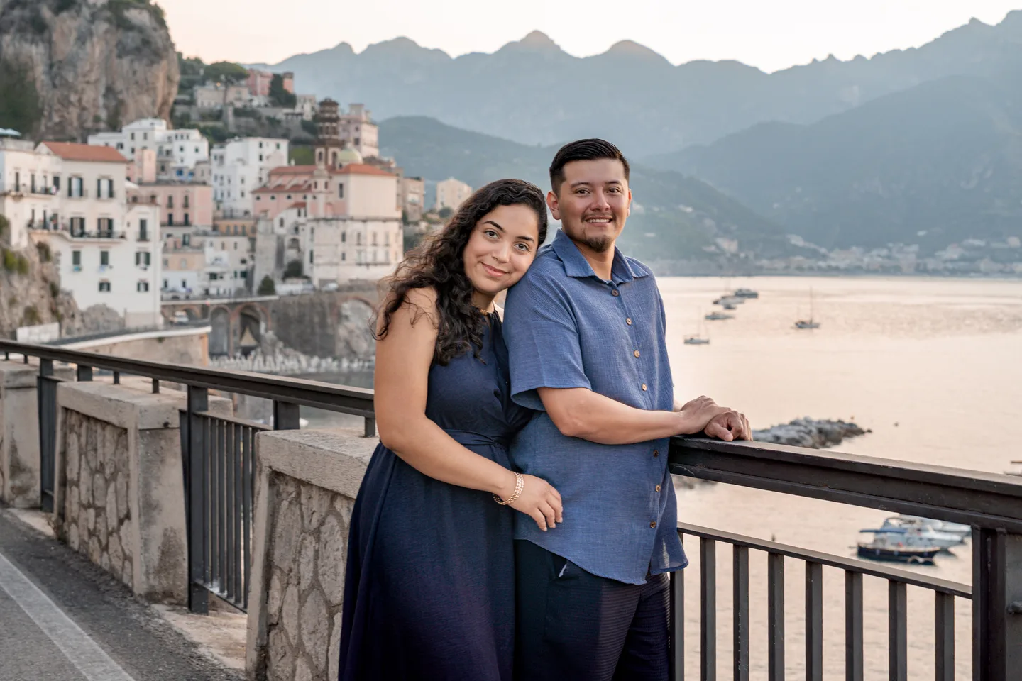 The couple embracing at the railing overlooking Atrani