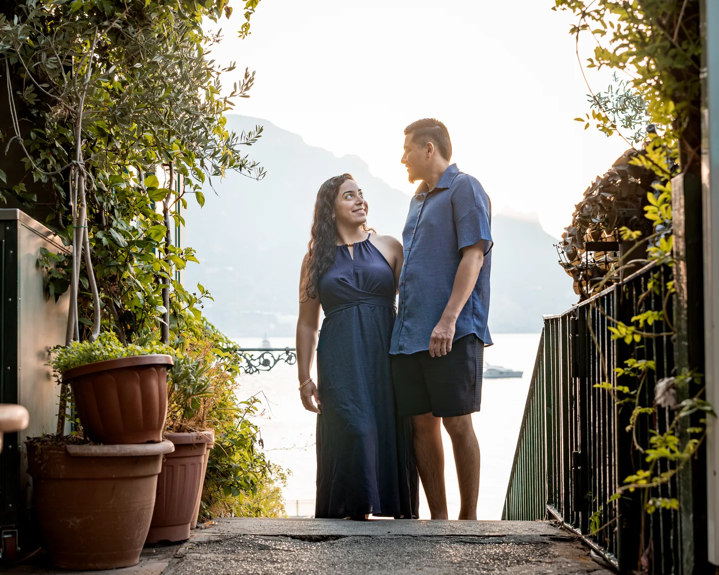 The couple framed by plants at the top of a stone staircase