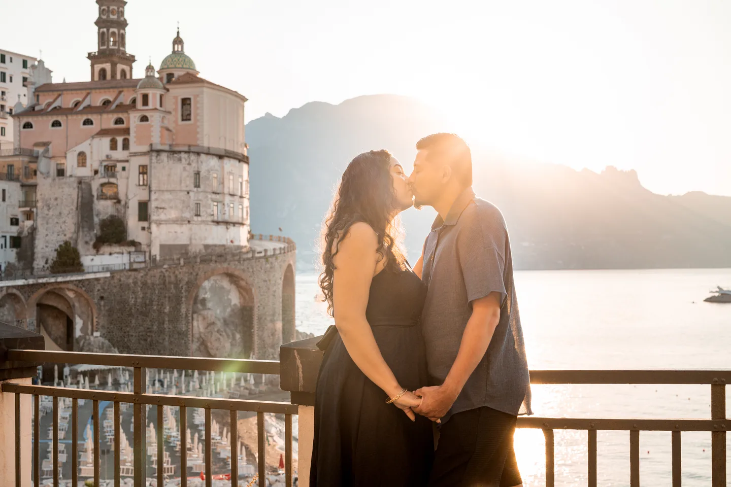 The couple kissing above the water in the sunrise