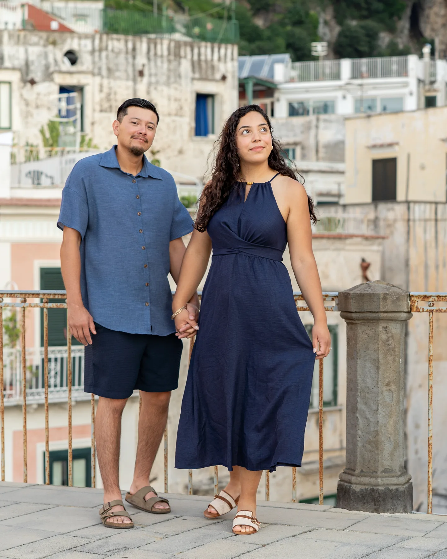 A full-length portrait of the couple by the village railing