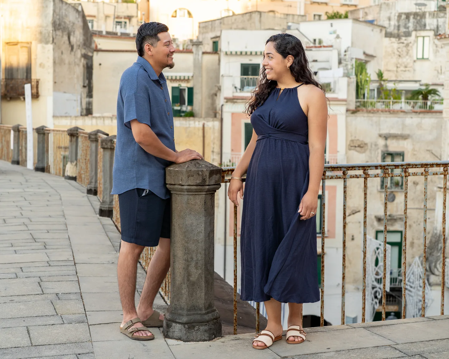 The couple holding hands beside the stone balustrade