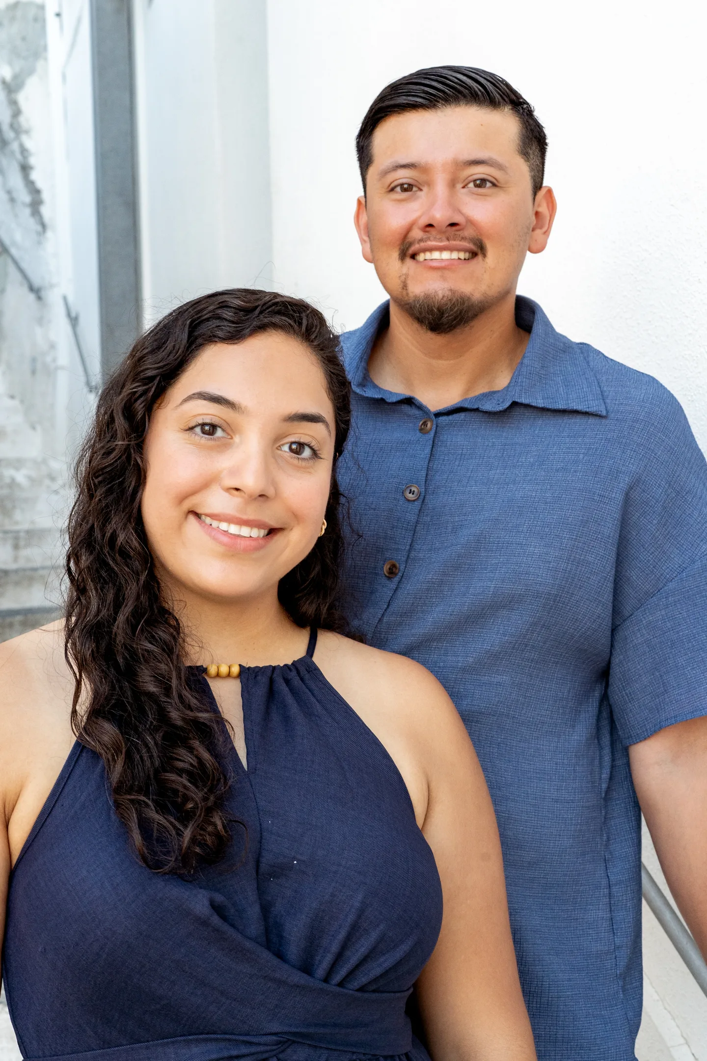 A close portrait of the couple beside a white wall