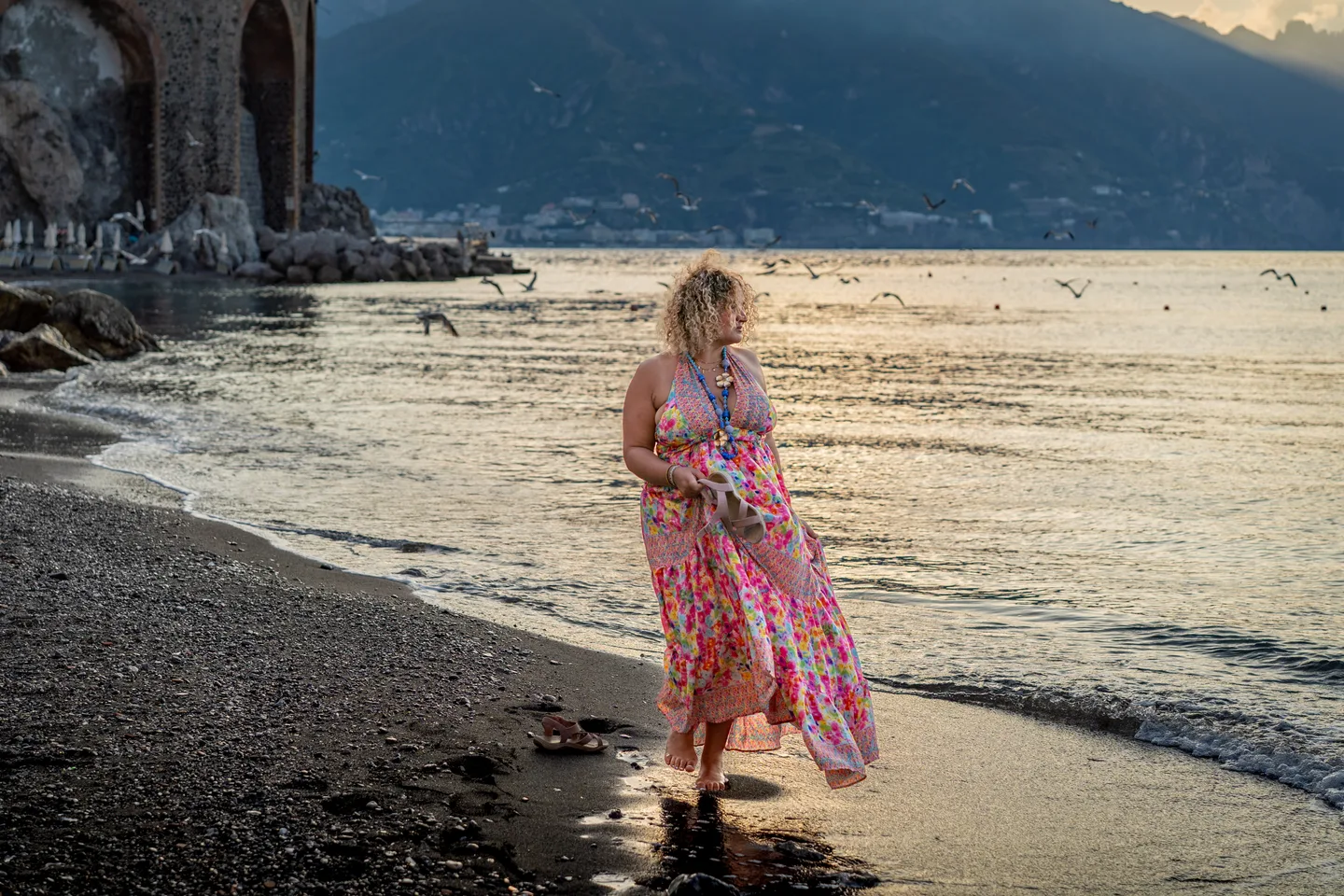 Hinad walking along the shore in a pink floral dress