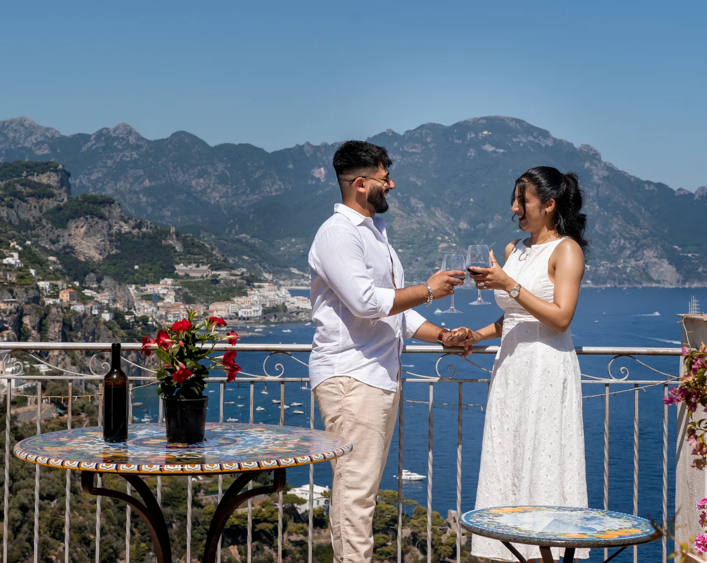 The couple raising their glasses above the sea