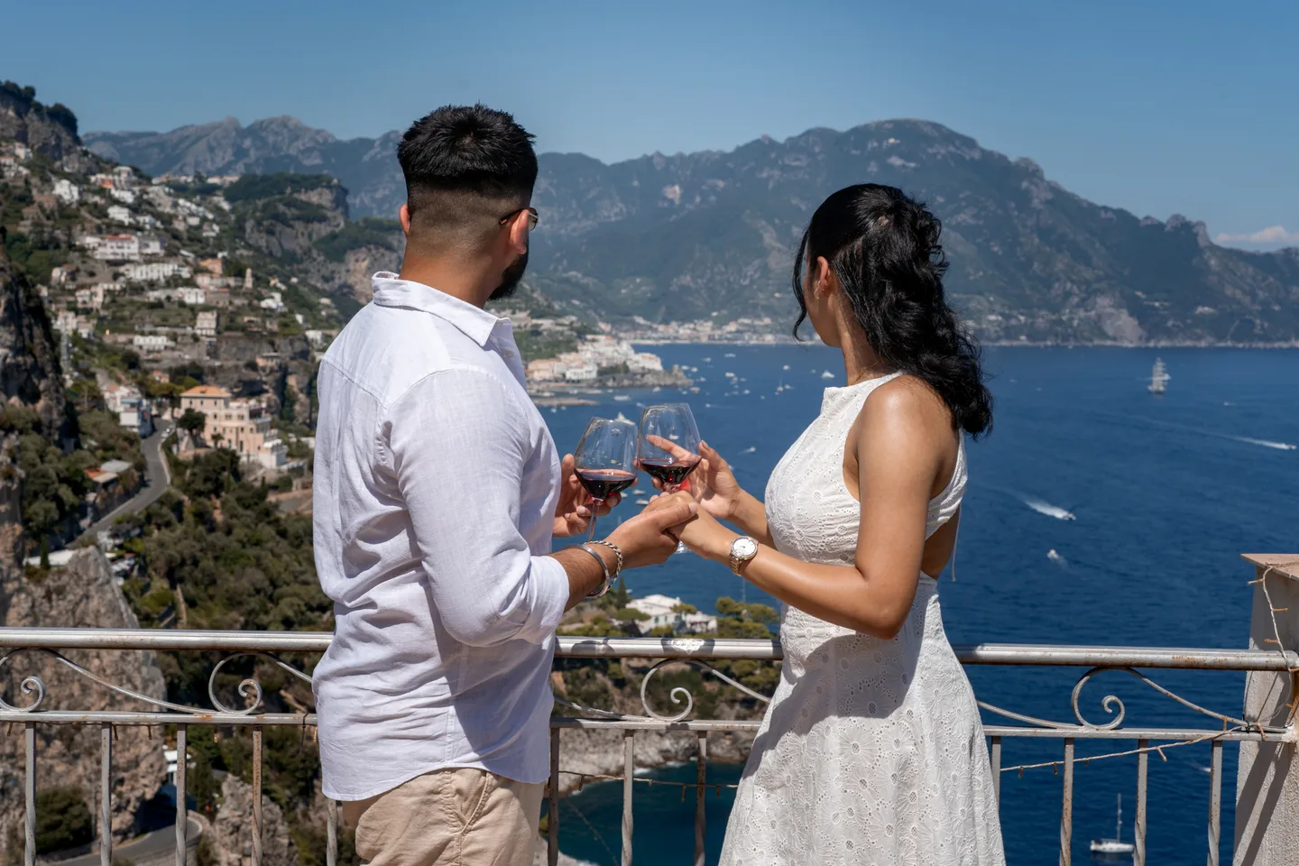 The couple enjoying wine with the coastline behind them