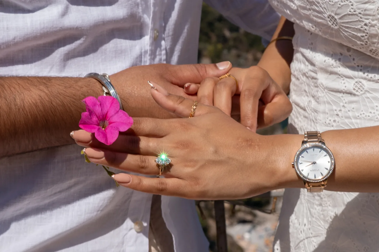 Their hands together with a small pink flower
