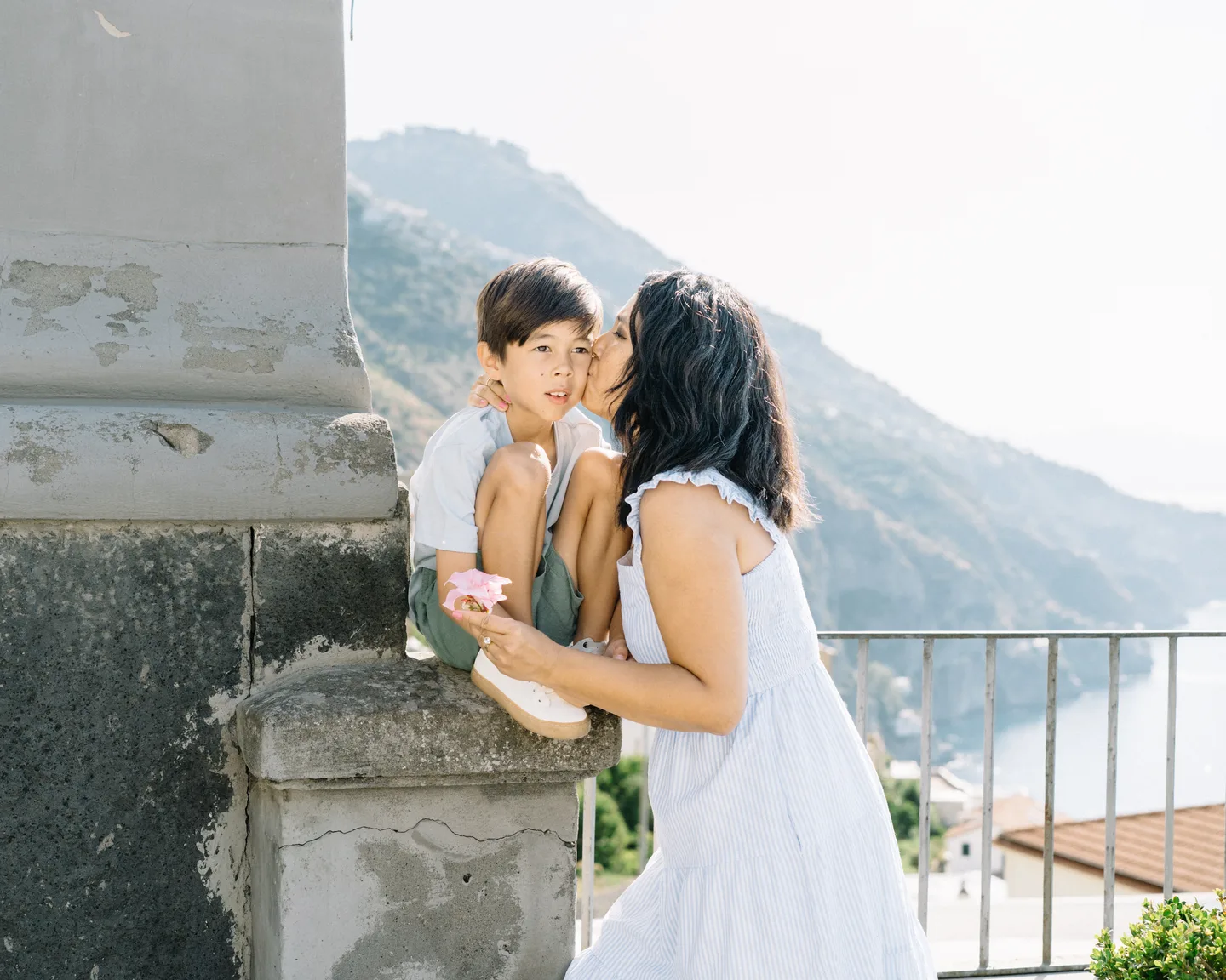 Mother and son sharing a kiss beside a stone column