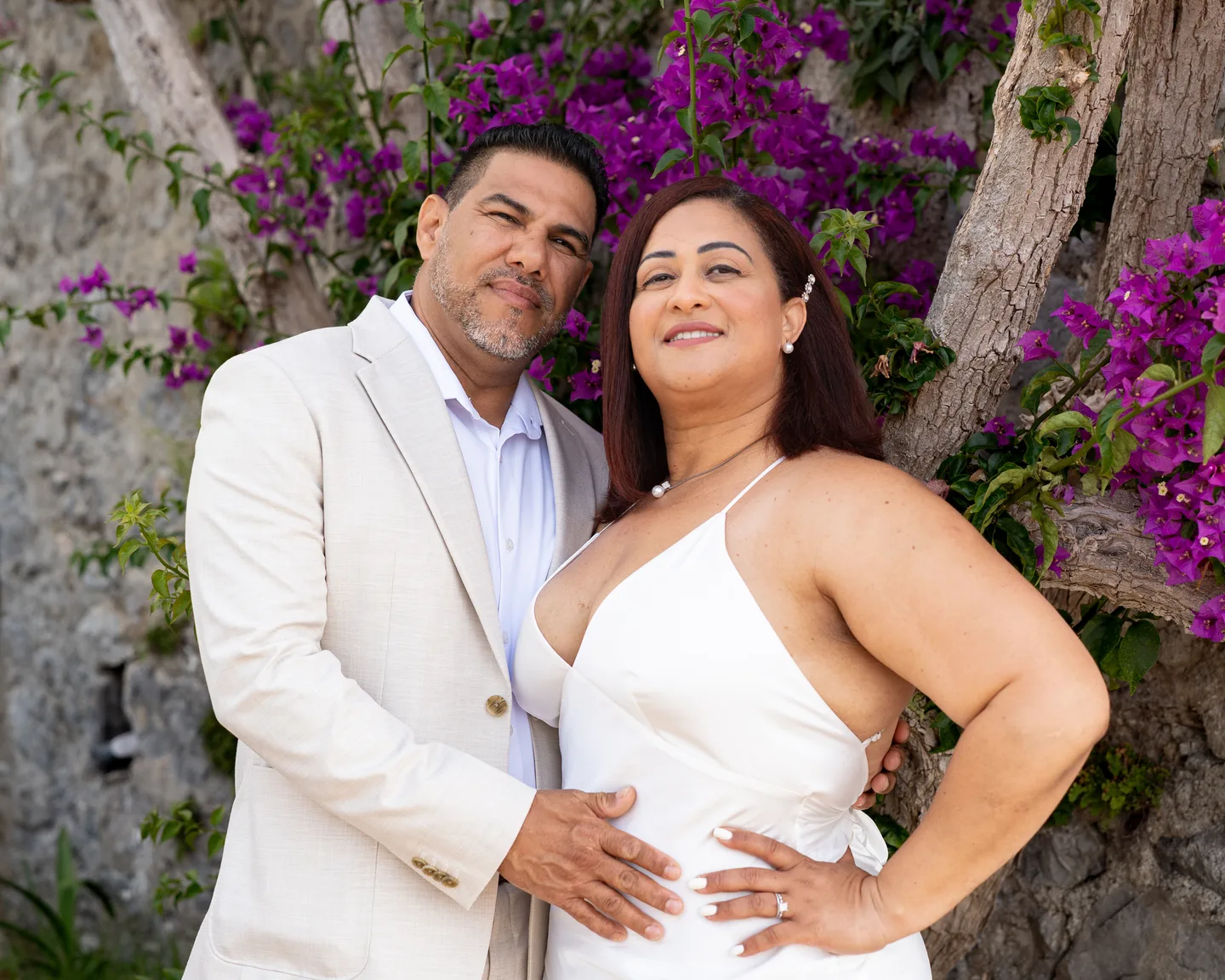 The couple embracing beside flowering bougainvillea