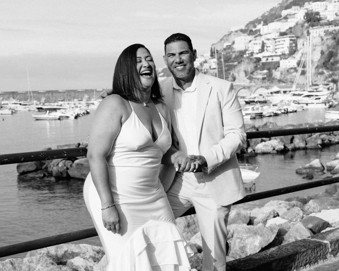 A black-and-white portrait of the couple at the waterfront railing