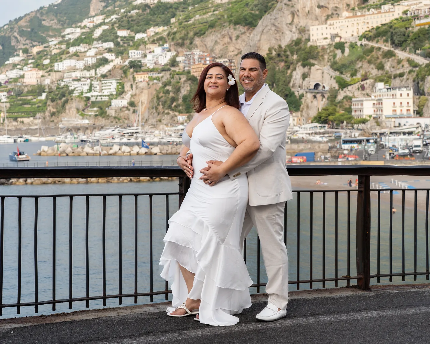 The couple embracing above the water with Amalfi behind them