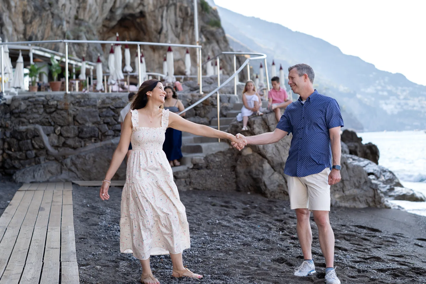 The couple holding hands in front of the beach steps