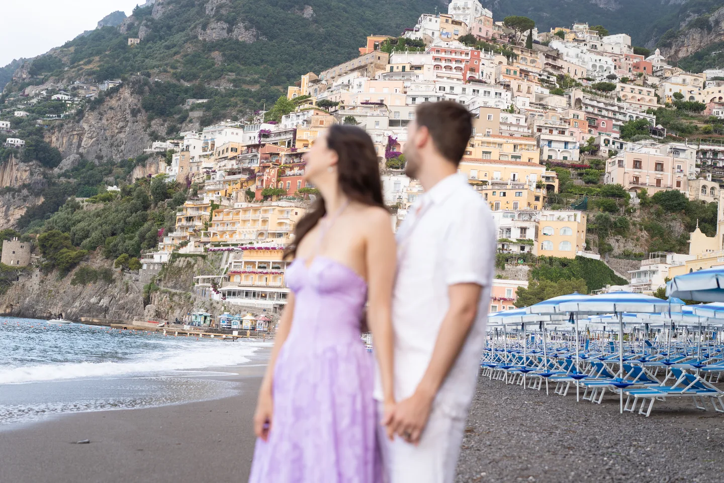 The couple holding hands and looking towards the town