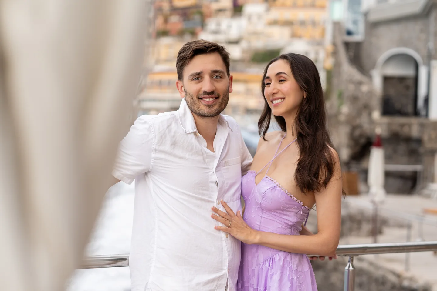 The couple smiling beside the waterfront café