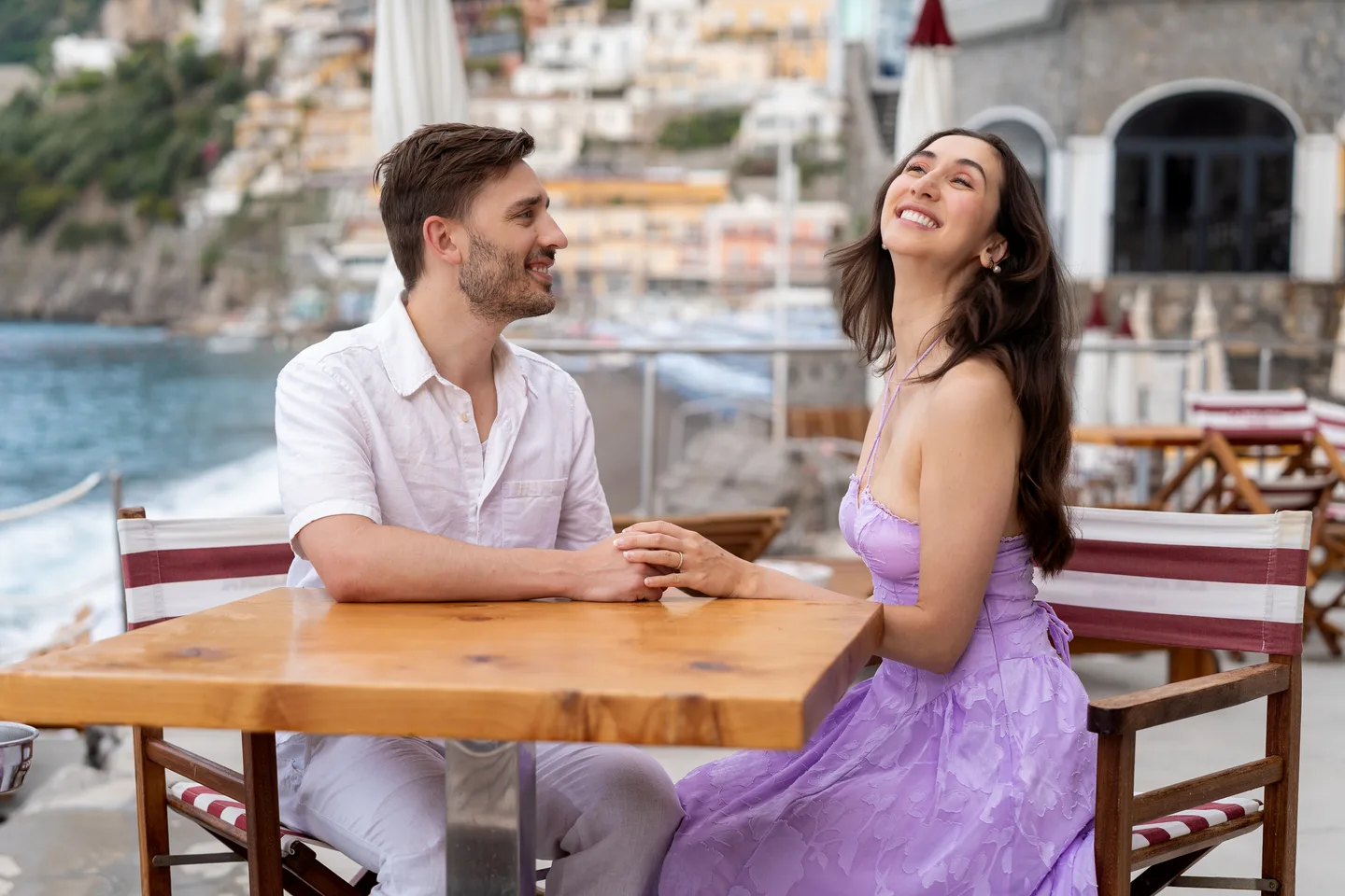 The couple laughing together at a wooden table