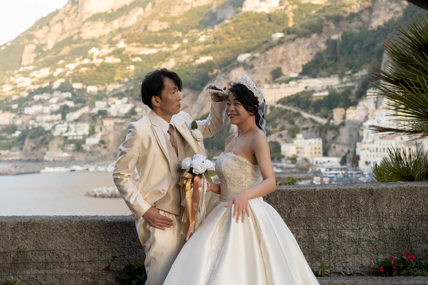 The couple smiling at one another beside the sea wall