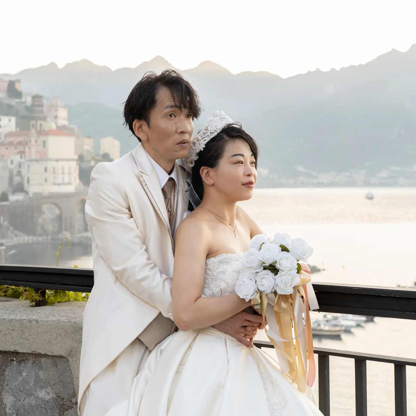 A close portrait of the couple and their bouquet above Atrani