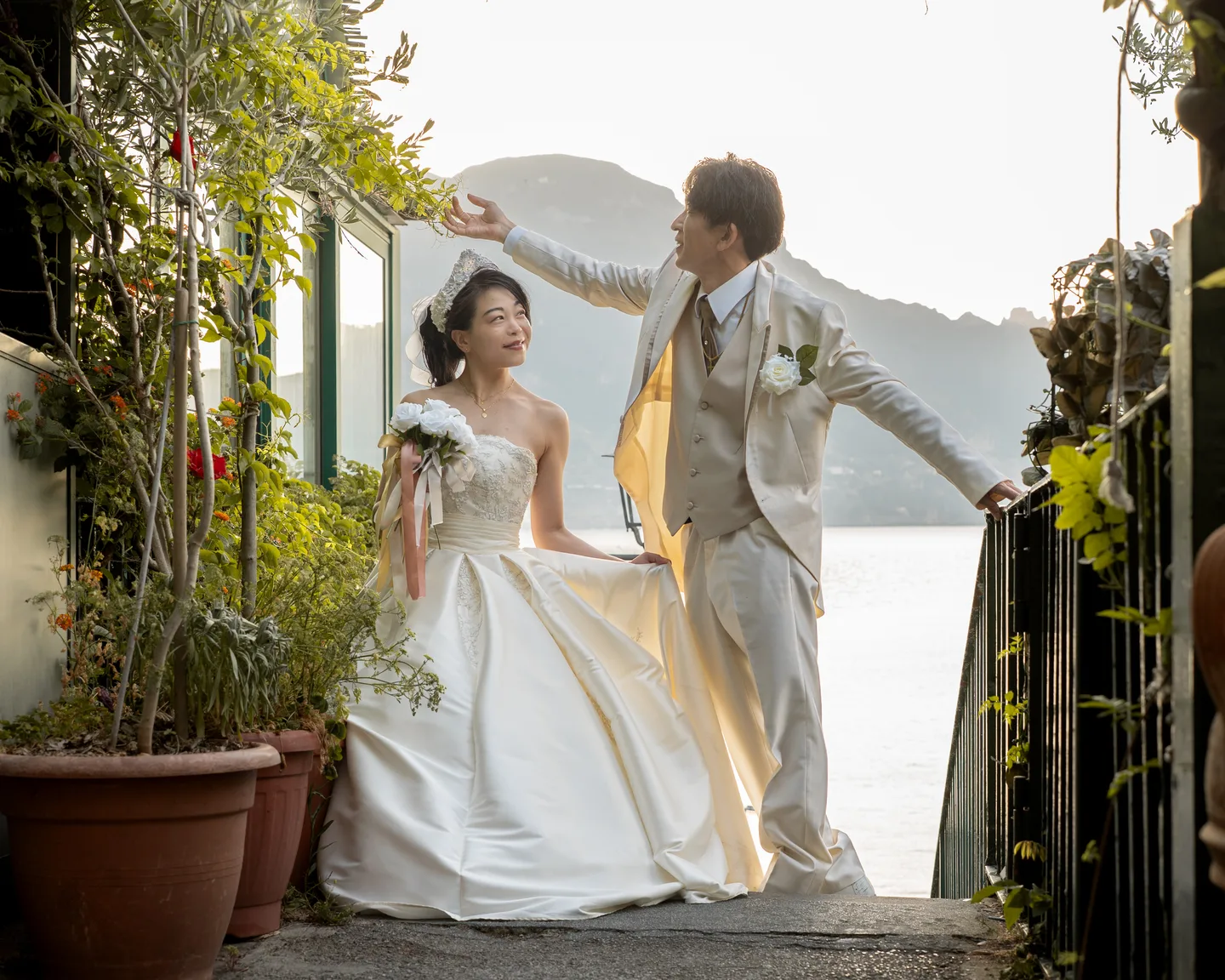 Takamasa raising his partner’s hand on a plant-lined staircase
