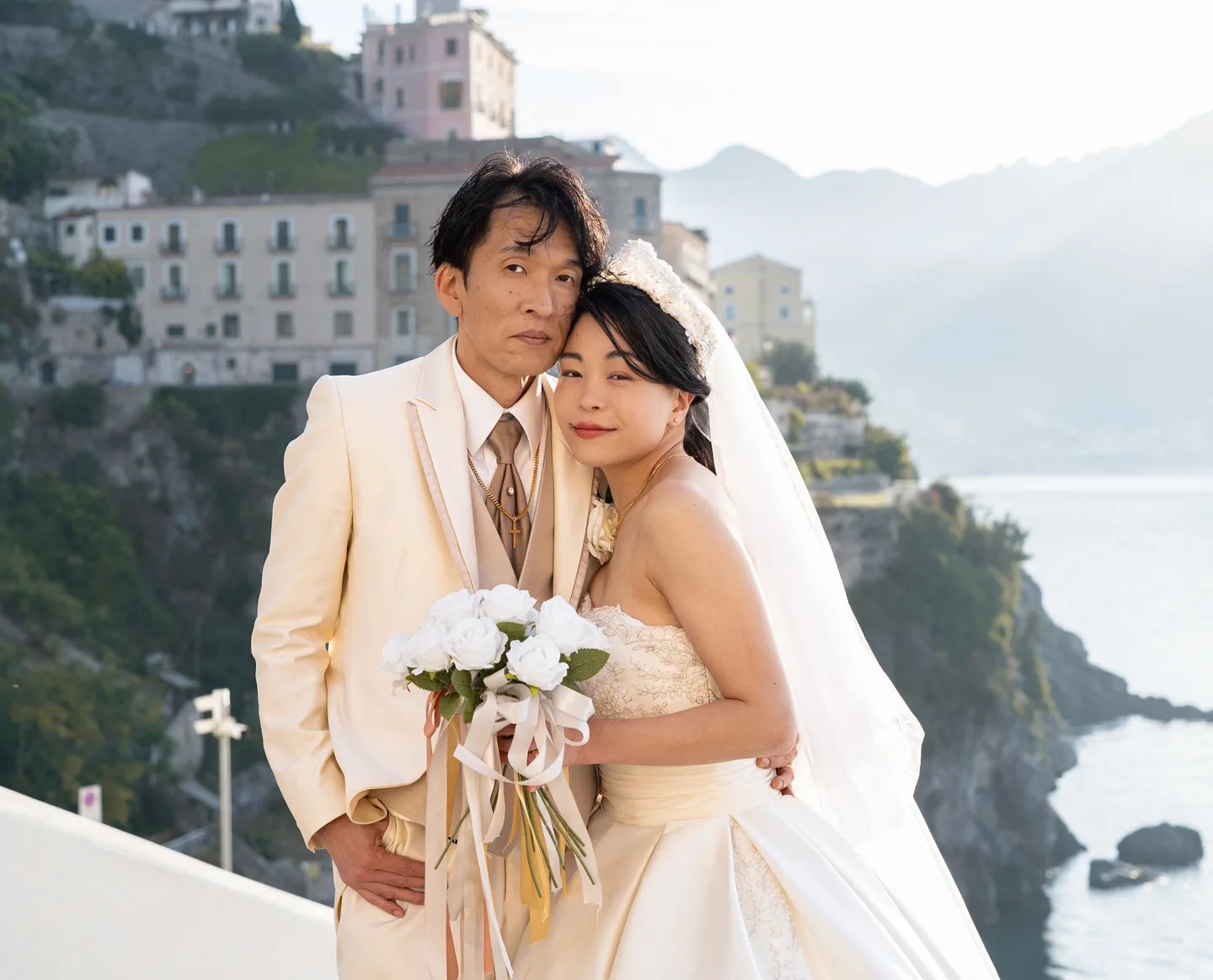 The couple embracing with Atrani behind them