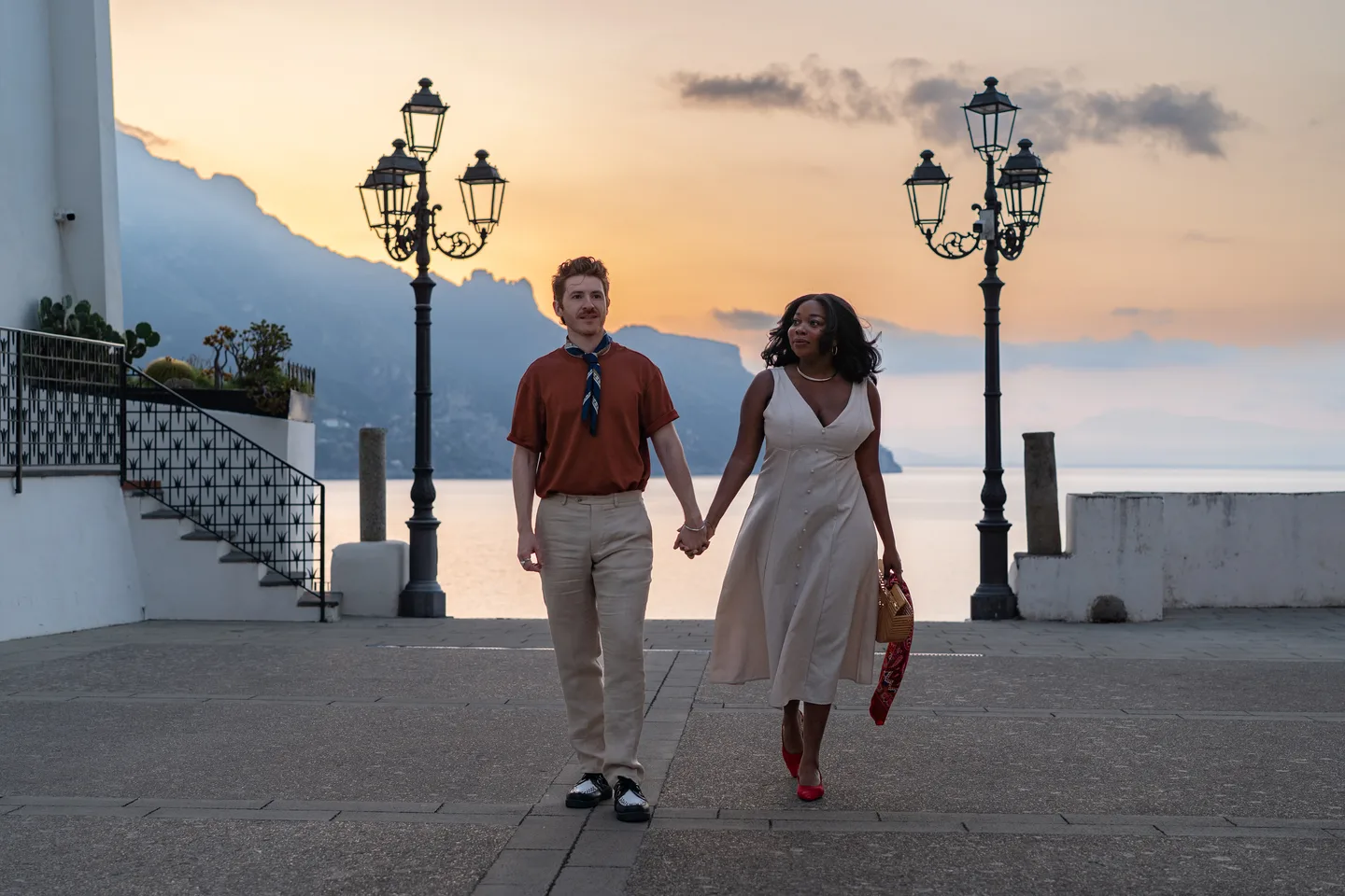 The couple holding hands beneath the sunrise sky