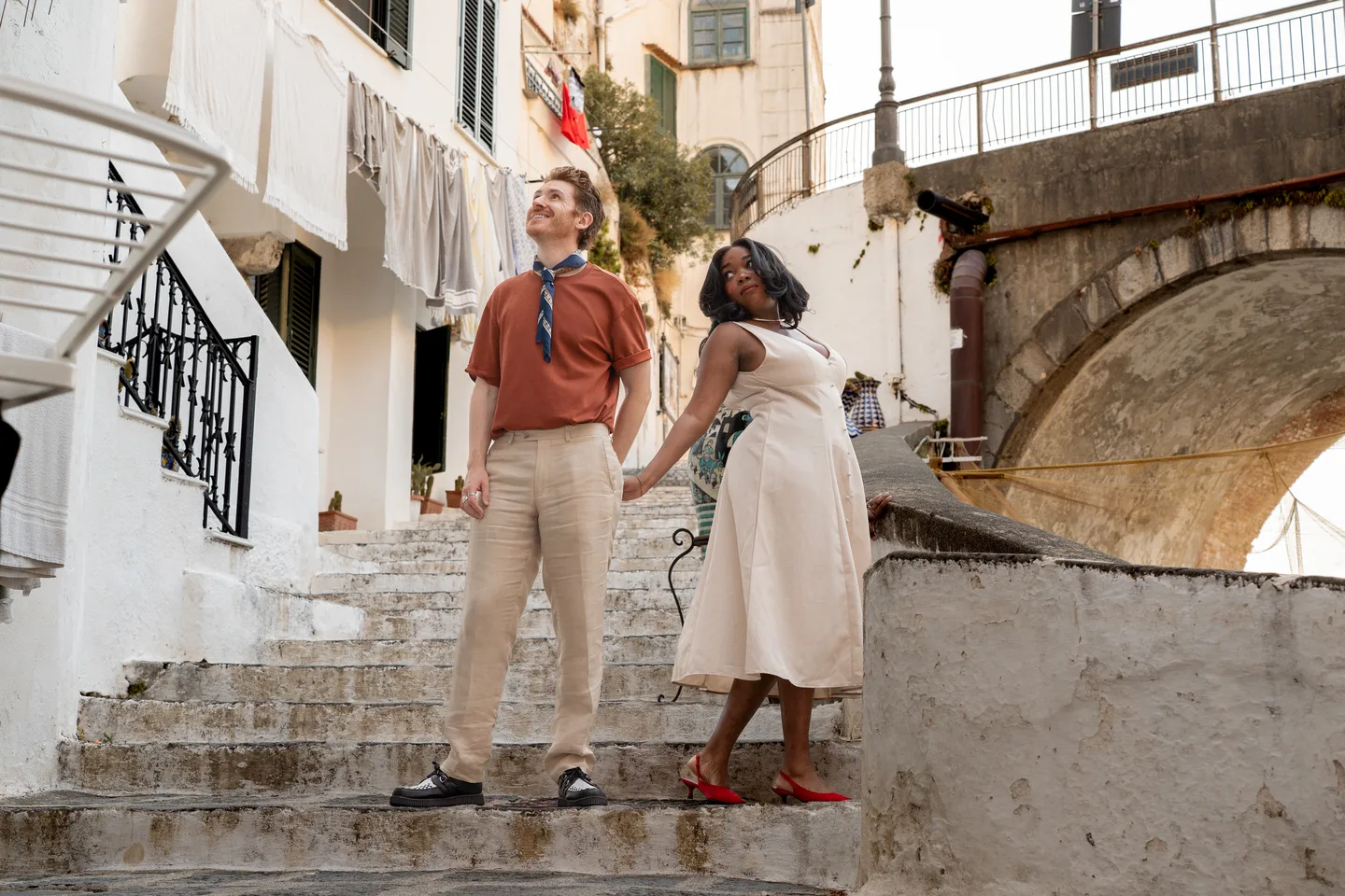 The couple standing below a small stone bridge